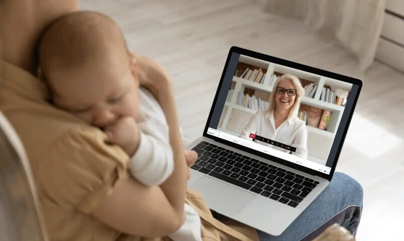 Moeder met baby op arm belt met kraamverzorgster via beeldbelprogramma WeSeeDo op Ipad